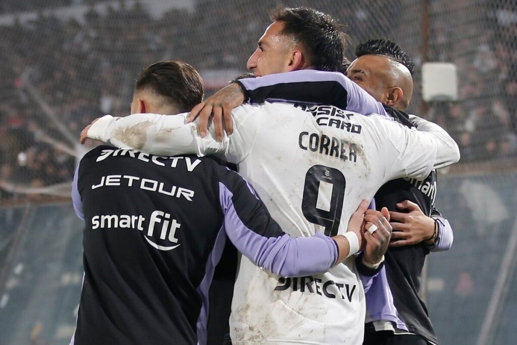 Jugadores de Colo-Colo abrazados celebrando un gol.
