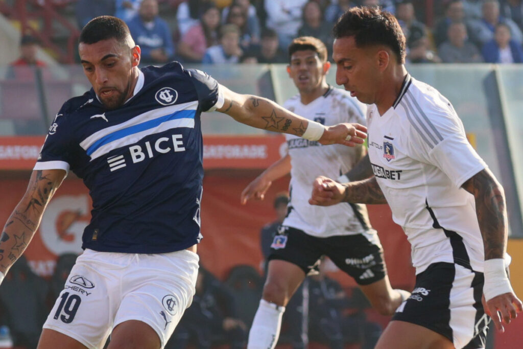 Javier Correa disputando un balón con Branco Ampuero durante un partido entre Colo-Colo y Universidad Católica.
